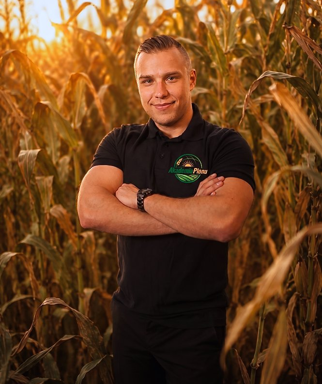 Jakub Czeczko, doradca rolniczy Akademii Plonu, stojący w polu kukurydzy o zachodzie słońca